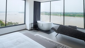 Une salle de bain moderne dotée d’une grande baignoire, d’une douche et offrant une vue sur un plan d’eau.