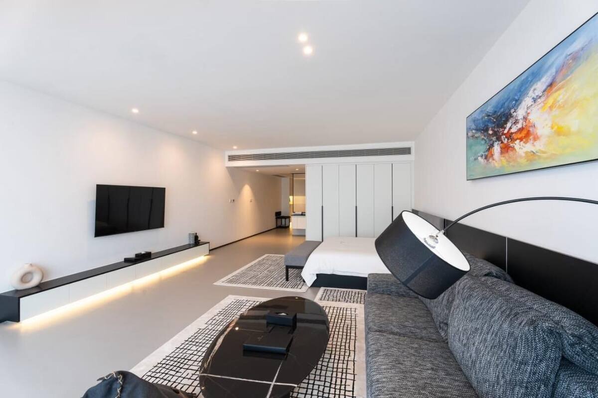 A modern living room with a sofa, a coffee table, a TV mounted on the wall, and a painting.