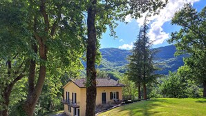 Une maison avec une allée pavée, un petit porche doté de sièges extérieurs et une vue sur un paysage montagneux.
