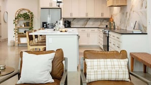 A modern kitchen with white cabinets, a marble backsplash, and a central island with seating.