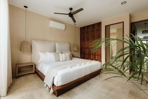 A bedroom with a bed, ceiling fan, bedside lamps, and a potted plant.