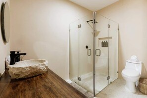 A bathroom with a stone sink, a glass shower enclosure, and a toilet.