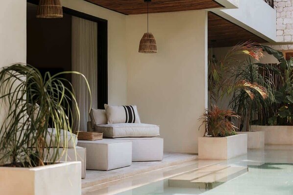 A modern indoor pool area with a sofa and potted plants.