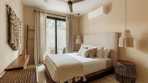 A bedroom with a bed, a desk, a chair, a round table, and a ceiling fan.