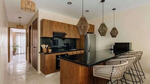 A modern kitchen with wooden cabinets, a black countertop, and a central island with bar stools.