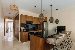 A modern kitchen with wooden cabinets, a black countertop, and a central island with bar stools.