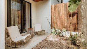 A patio with two wicker chairs, a small round table, and a bamboo fence.