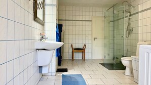 A bathroom with a white sink, a mirror, a shower, and a toilet.