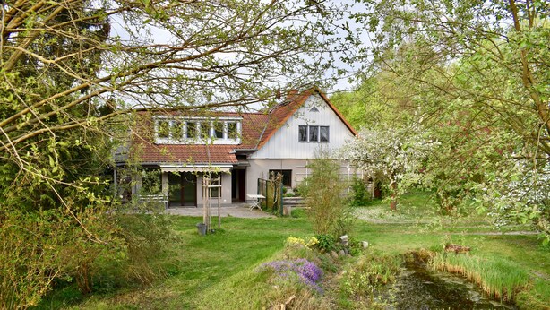 A house with a garden, a pond, and a small bridge.