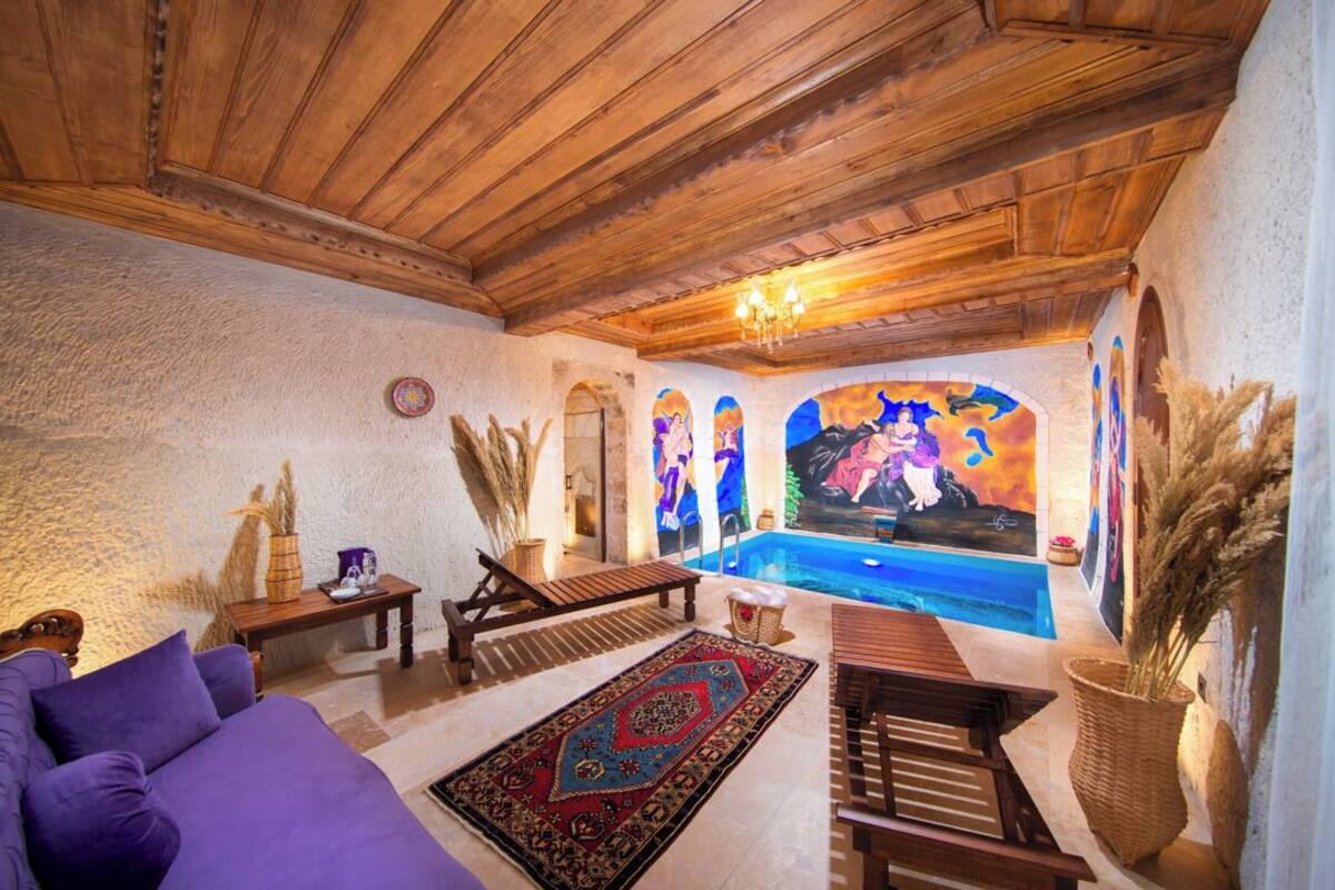A room with a wooden ceiling, a pool, a purple sofa, and a colorful mural.