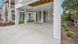 Ein modernes, zweistöckiges Haus mit überdachter Terrasse, Treppe und gepflegtem Rasen.