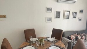 A dining area with a round wooden table set for four, surrounded by brown upholstered chairs. - Mise au Vert F2 à 5 mns des Commerces et 2 mns des Thermes Mer et la Montage (Amélie-les-Bains-Palalda)