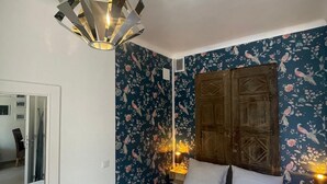 A bedroom with a bed, a wooden wardrobe, and a ceiling light fixture. - Mise au Vert F2 à 5 mns des Commerces et 2 mns des Thermes Mer et la Montage (Amélie-les-Bains-Palalda)