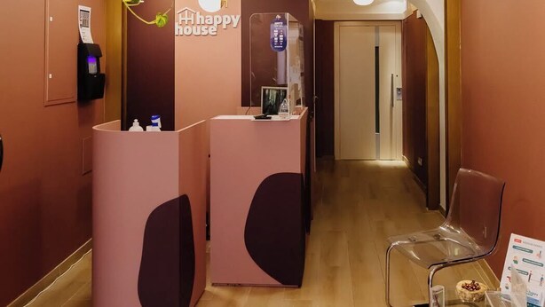 A reception area with a modern design, including a reception desk, a plant, and a clear glass partition. - Deluxe Double Room (Faro)