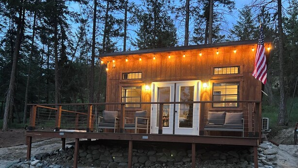 A cabin with a deck, outdoor seating, and an American flag.