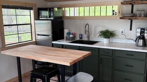 A modern kitchen with a wooden ceiling, a built-in microwave, a refrigerator, a sink, and a coffee maker.