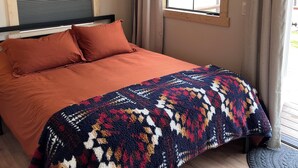 A bedroom with a bed, a window, and curtains.