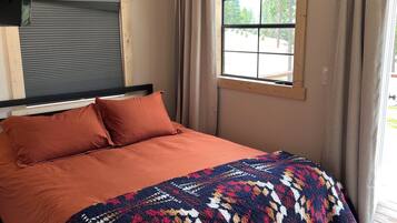 Une chambre à coucher avec un lit, une fenêtre et des rideaux.