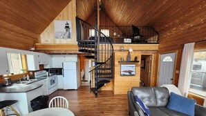 Una cabaña acogedora con cocina, comedor y sala de estar con sofá y chimenea.