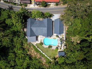 An aerial view of a residential property with a swimming pool, multiple roofed structures, and surrounding greenery. - Villa Olympus 4 bedrooms Sea view Kata beach with pool and tropical garden (Tambon Karon)