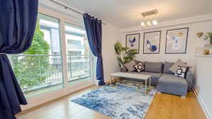 Una sala moderna con sofá, mesa de centro y un ventanal con cortinas.