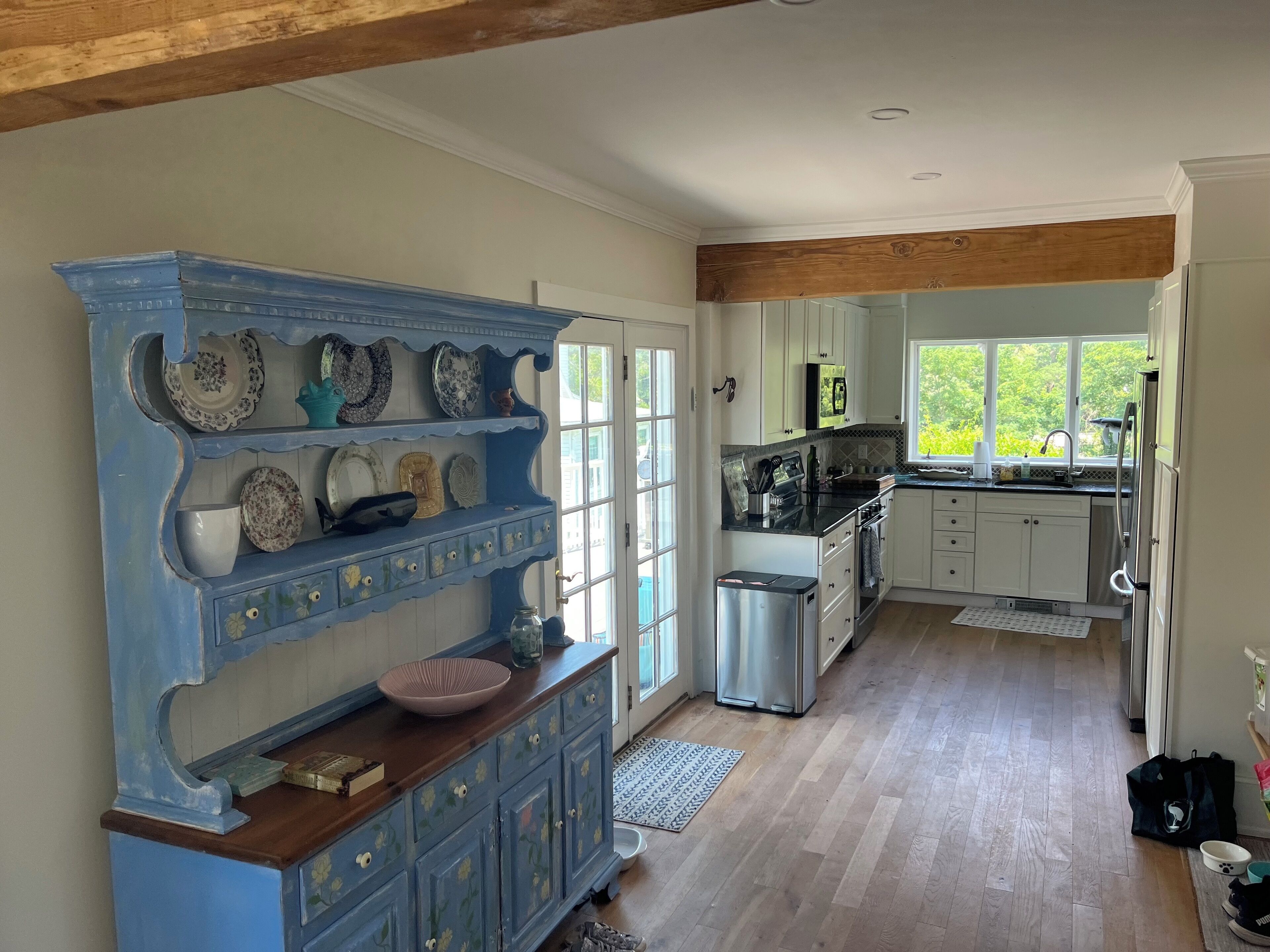 A kitchen with white cabinets, a blue decorative shelf, and a stainless steel refrigerator.