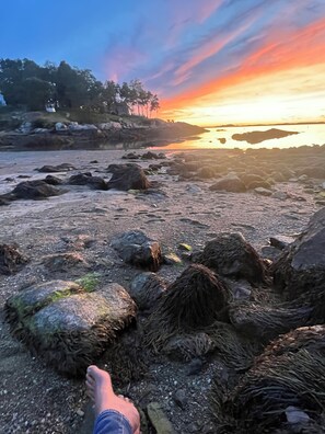 Une plage de galets avec un coucher de soleil en arrière-plan.