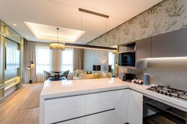 A modern kitchen with a central island, built-in appliances, and a dining area with a chandelier. - Steyn City Hotel by Saxon (Midrand)