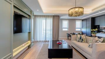 A modern living room with a black coffee table, a beige sofa, and a large TV mounted on the wall.