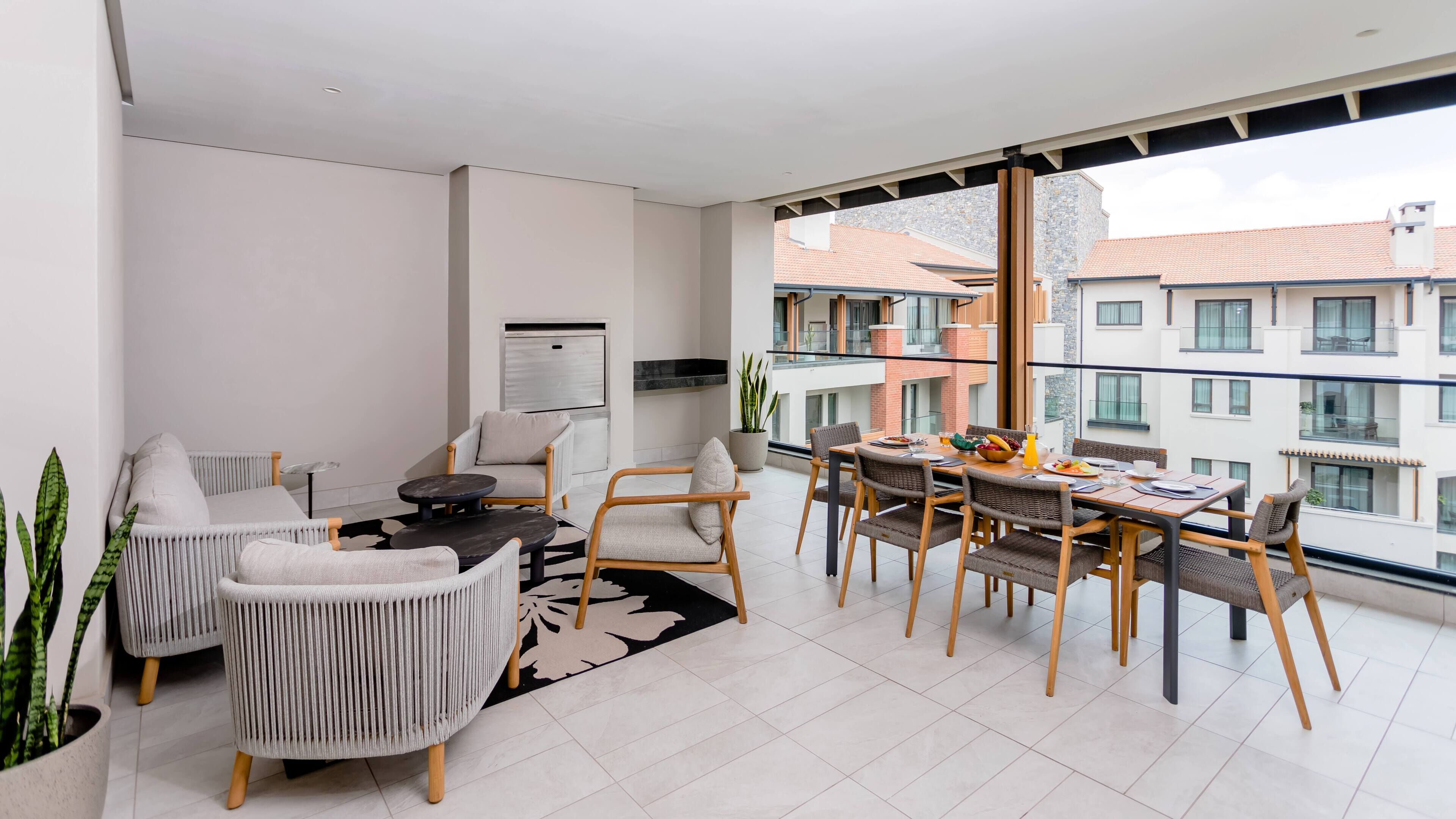 A modern apartment with a dining area, seating, a kitchen, and a balcony with a view of buildings.