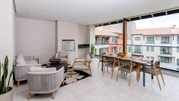 A modern apartment with a dining area, seating, a kitchen, and a balcony with a view of buildings.