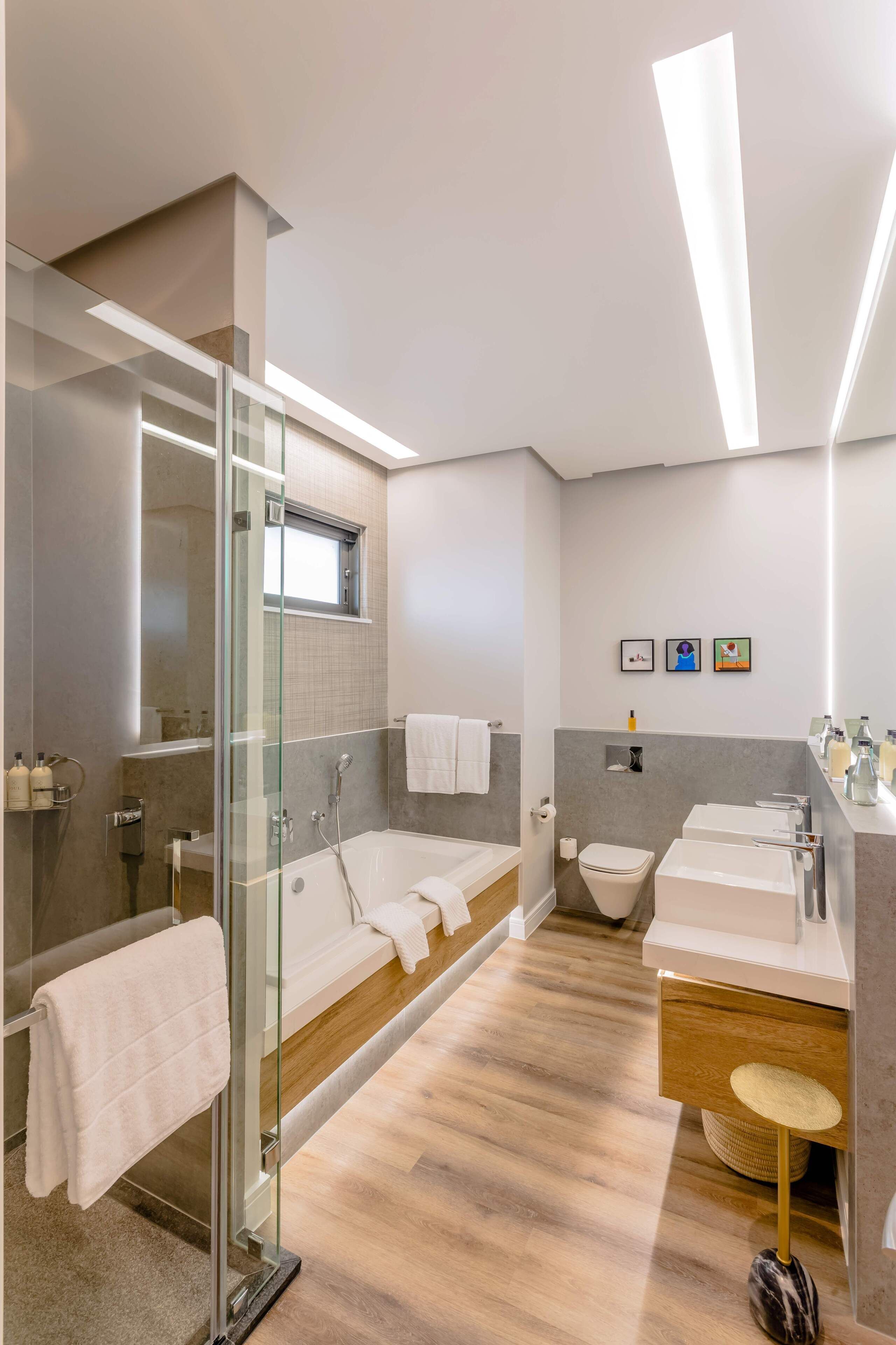 Un baño moderno con cabina de ducha de vidrio, una bañera, un inodoro y un lavabo con espejo.