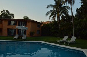 A swimming pool with lounge chairs and an umbrella, surrounded by a house and palm trees. - Casa Mora Mexican House. Great for Families. Walking Distance From the Beach (Ixtapa Zihuatanejo)