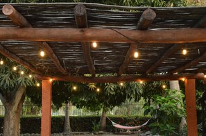 A wooden pergola structure with string lights, a hammock, and lush greenery in the background. - Casa Mora Mexican House. Great for Families. Walking Distance From the Beach (Ixtapa Zihuatanejo)
