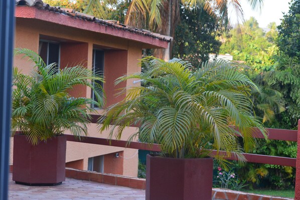 A building with a red-tiled roof and a balcony with potted palm plants. - Casa Mora Mexican House. Great for Families. Walking Distance From the Beach (Ixtapa Zihuatanejo)