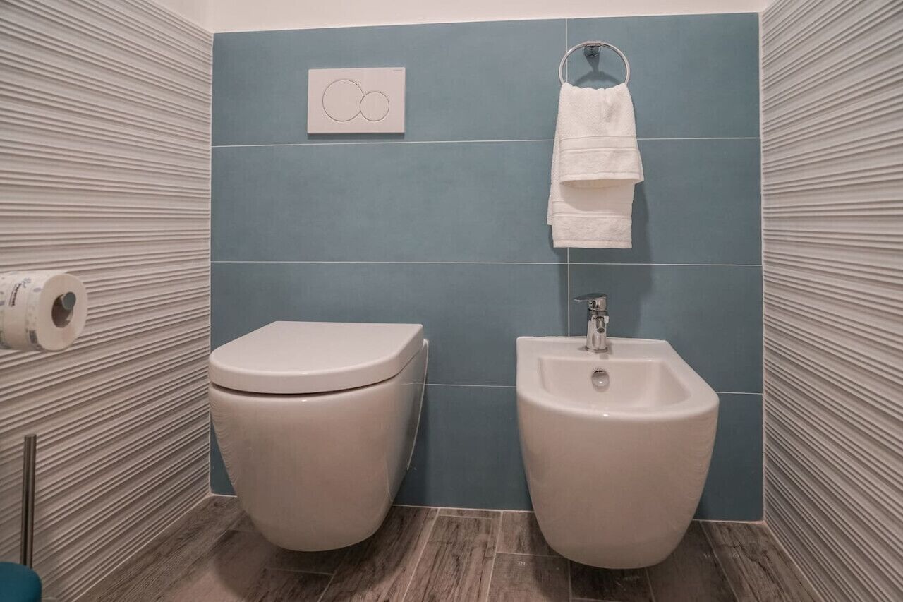 Een badkamer met toilet, hygiëneschuimer en handdoekhouder.