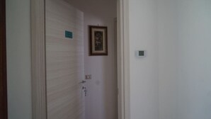 Eine geschlossene Tür mit einem kleinen Schild an der Wand, einem Lichtschalter und einem gerahmten Bild darüber.