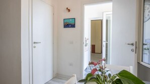 Un couloir avec une table à manger et des chaises, une petite plante et une porte donnant sur une autre pièce.