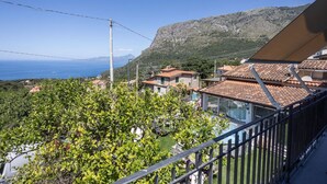 Un quartier résidentiel avec des maisons, une vue dégagée sur la mer et une montagne en arrière-plan.