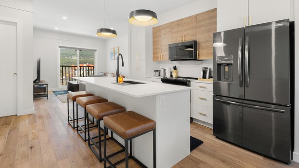 A modern kitchen with a central island, stainless steel appliances, and a view to the outdoors.