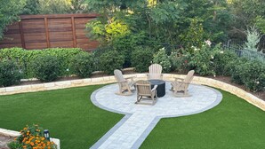 A patio area with a circular seating arrangement, a stone border, and a central planter with orange flowers. - Hilltop Haven Retreat in Texas Hill Country.  Kid/Pet friendly.  Pool & Firepit (The Hills)
