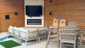 A cozy indoor seating area with a stone fireplace, a flat-screen TV, and wooden walls. - Hilltop Haven Retreat in Texas Hill Country.  Kid/Pet friendly.  Pool & Firepit (The Hills)