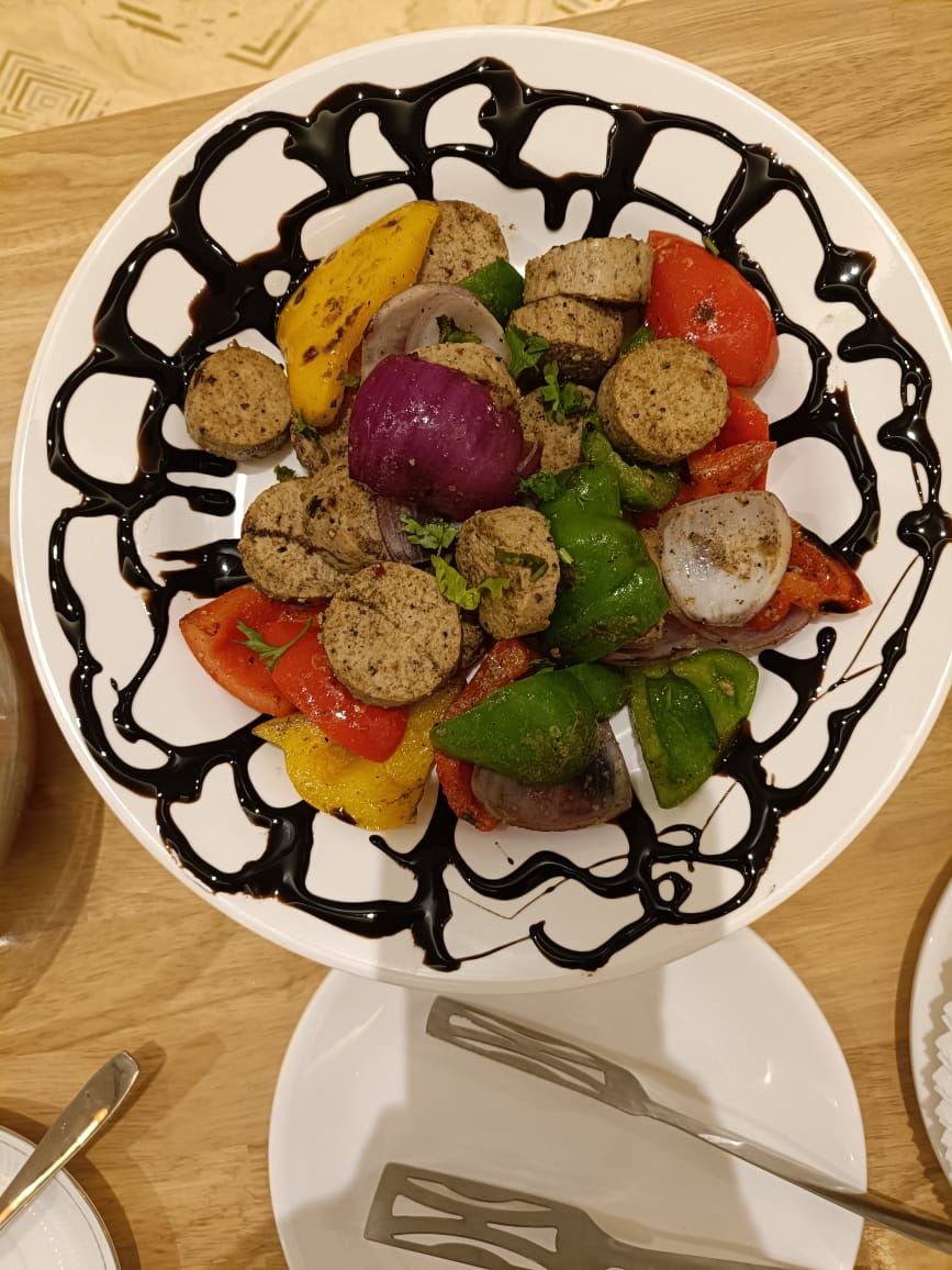 A plate of food with various vegetables and meatballs, garnished with a chocolate drizzle.