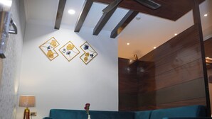 A modern living room with a blue sofa, a wooden coffee table, and a vase with flowers. - THE ON TIME HOTEL Bangalore (Bengaluru)