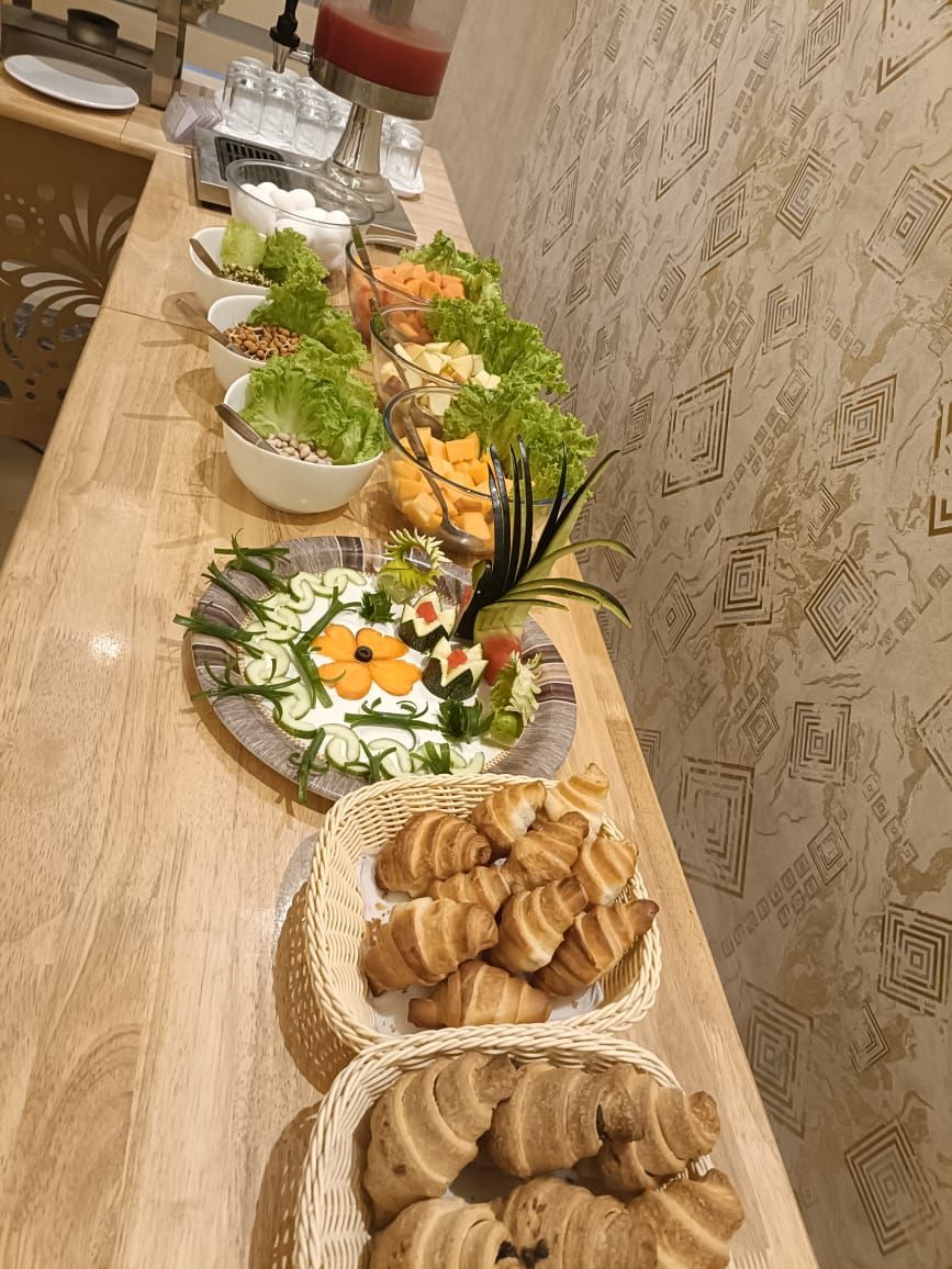 A buffet table with various food items including salads, cheeses, and pastries.