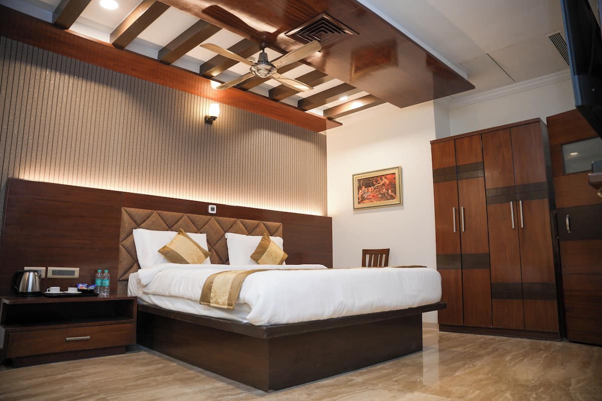 A modern hotel room with a large bed, wooden headboard, and a ceiling fan.