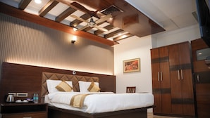 A modern hotel room with a large bed, wooden headboard, and a ceiling fan. - THE ON TIME HOTEL Bangalore (Bengaluru)