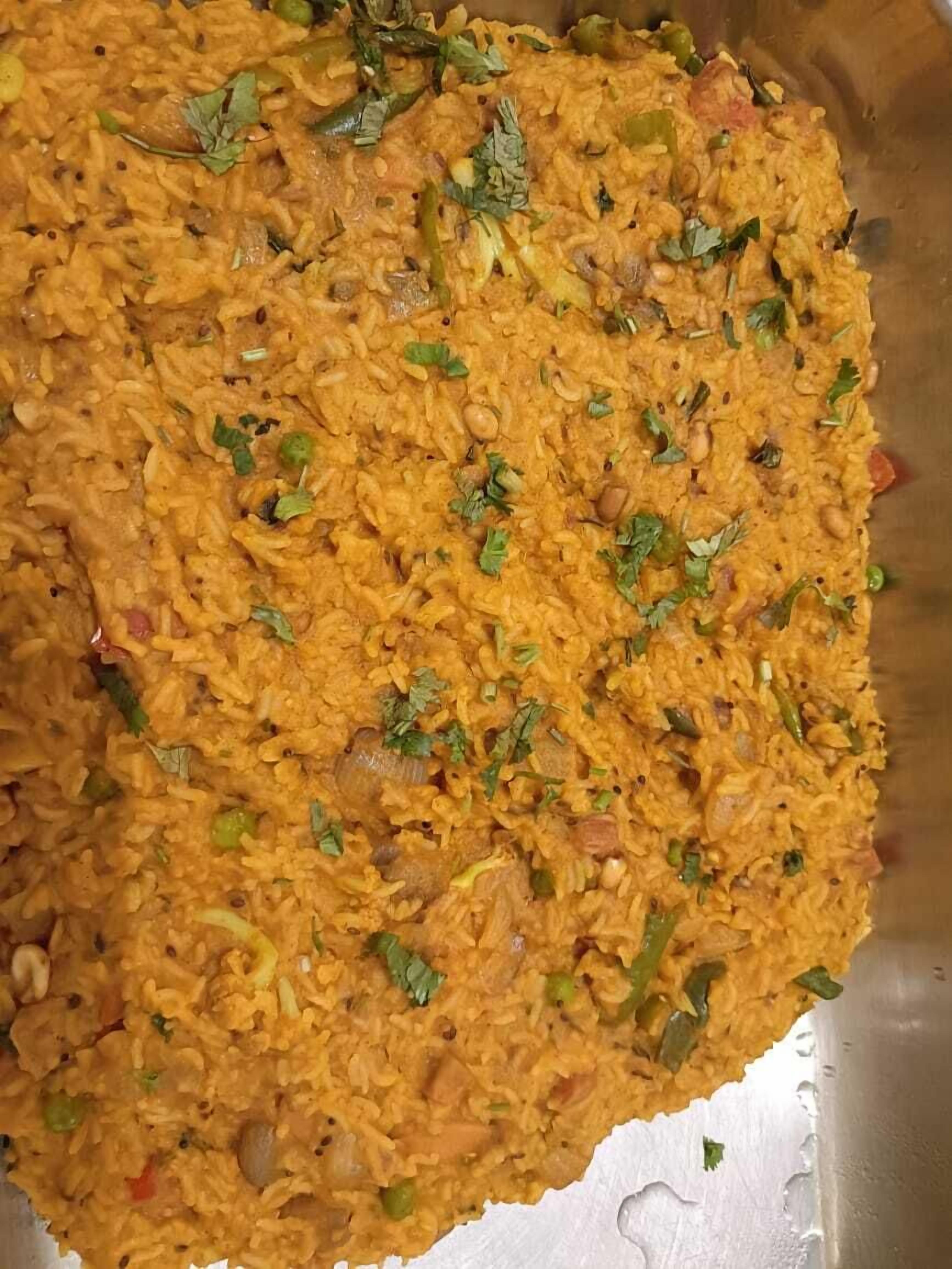 A large metal tray filled with a yellow rice dish garnished with herbs.