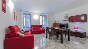 A modern living room with red sofas, a dining table, and a TV. - Carlo Alberto House by Wonderful Italy (Turin)