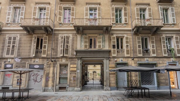 A historic building with multiple balconies, a central entrance, and outdoor seating areas. - Carlo Alberto House by Wonderful Italy (Turin)